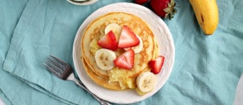 Banana split greek yogurt pancakes topped with strawberries and bananas on a plate