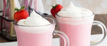Strawberry hot chocolate in a glass mug topped with whipped cream and a strawberry