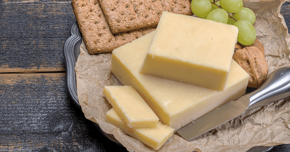 Blocks of white cheddar, grapes and crackers on a silver tray