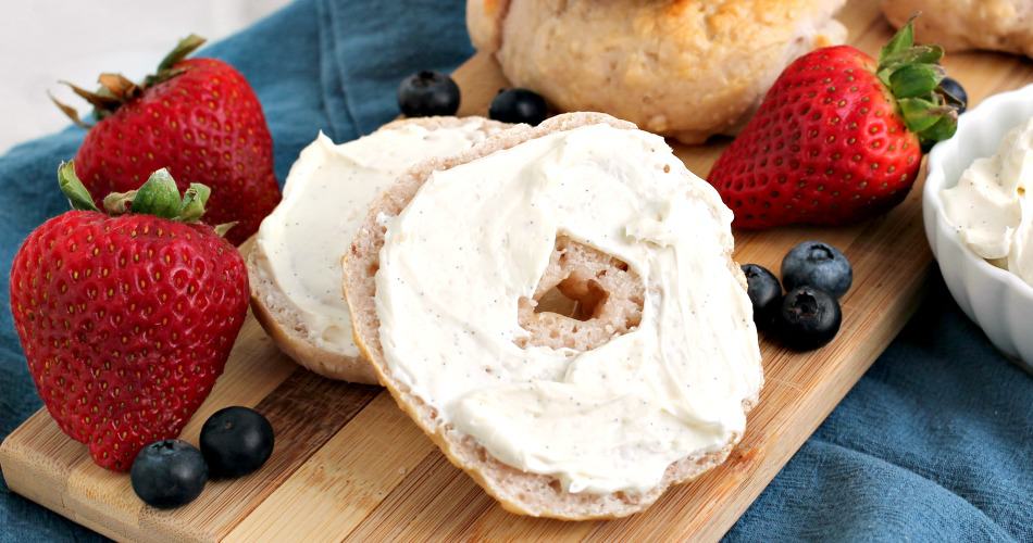 Sliced mixed berry Greek yogurt bagel covered with cream cheese on a wooden tray