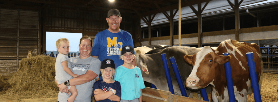 Bertke family standing in barn in front of cows.