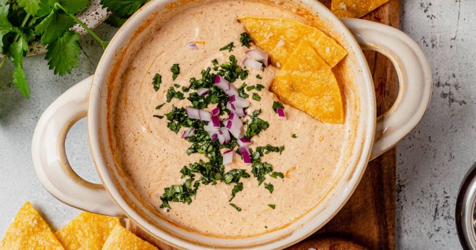 Creamy cottage cheese queso dip with herbs and tortilla chips, served in a bowl.
