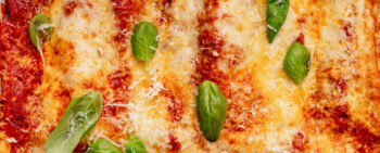 Close up of Cottage Cheese Manicotti on a plate with basil leaves spread out on top