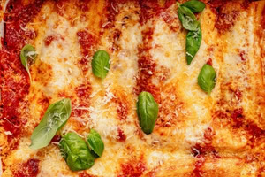 Close up of Cottage Cheese Manicotti on a plate with basil leaves spread out on top